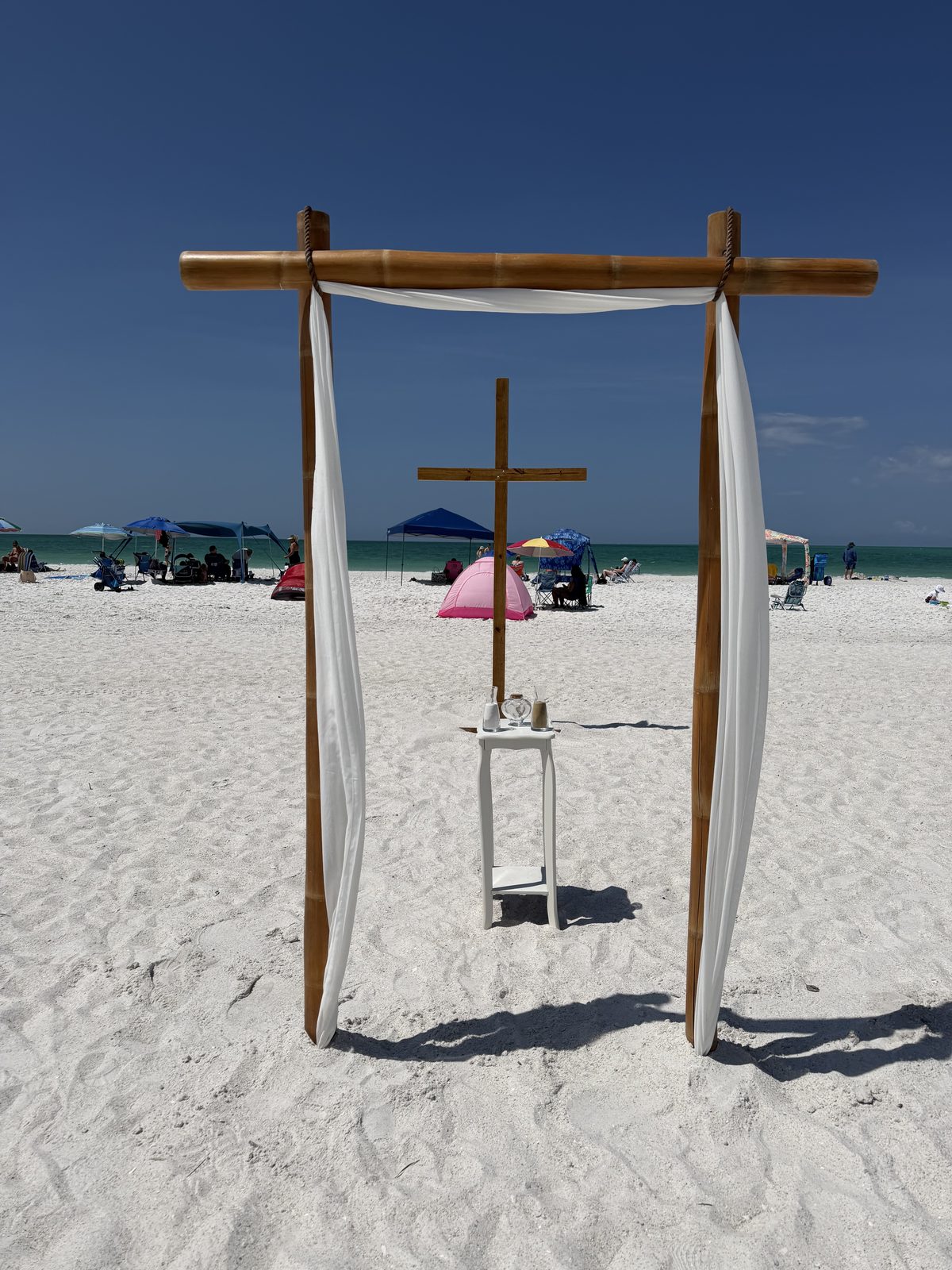 The cross standing inside a draped bamboo arch with a unity table